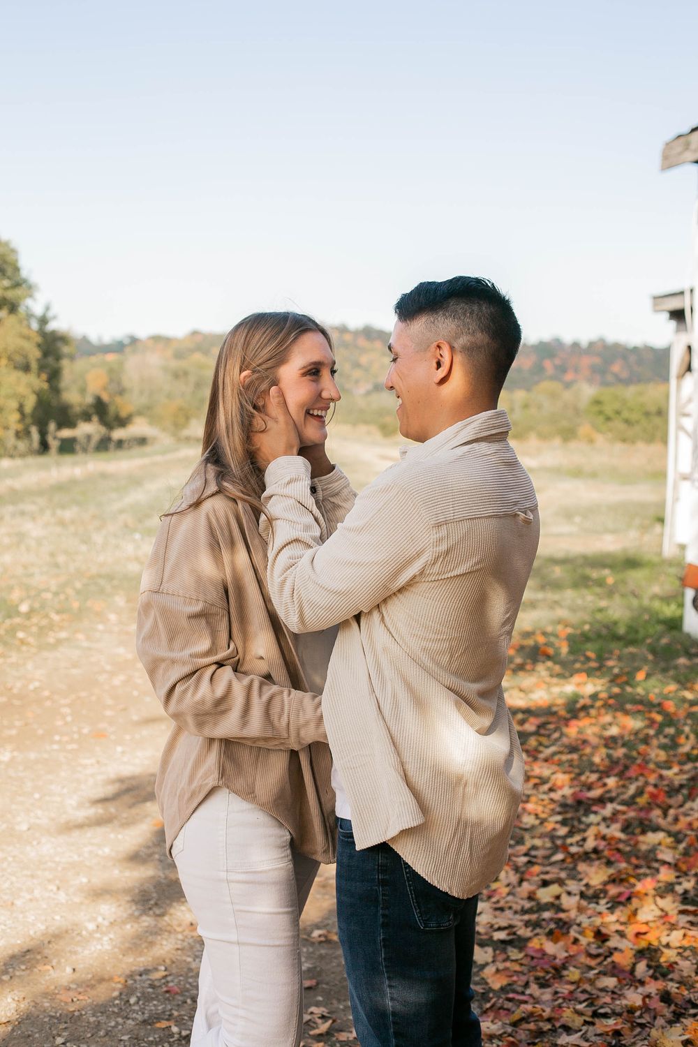 Romantic couple in neutral tones sharing intimate moment on autumn trail.