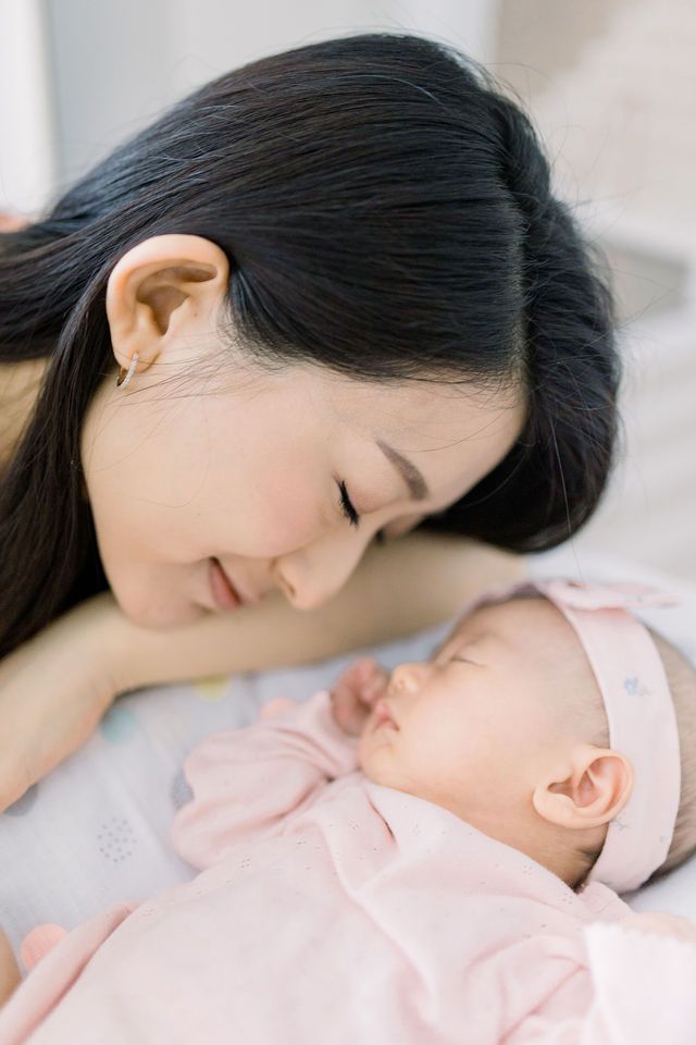 Tender moment between parent and sleeping baby in soft pink clothing.