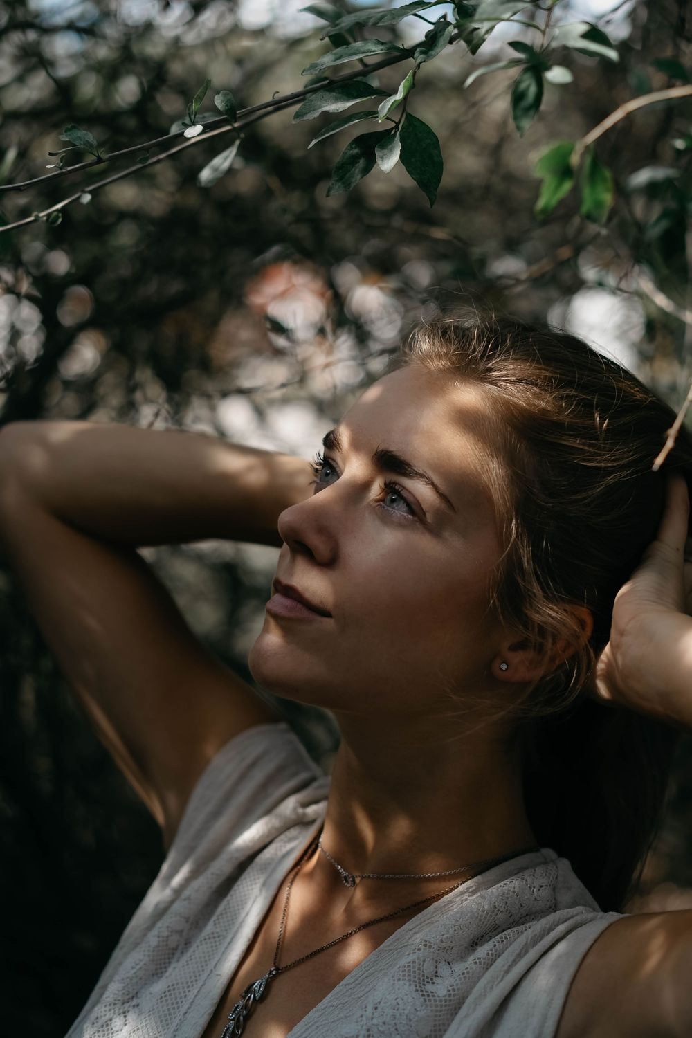 Woman in a white dress looking up and holding her hair