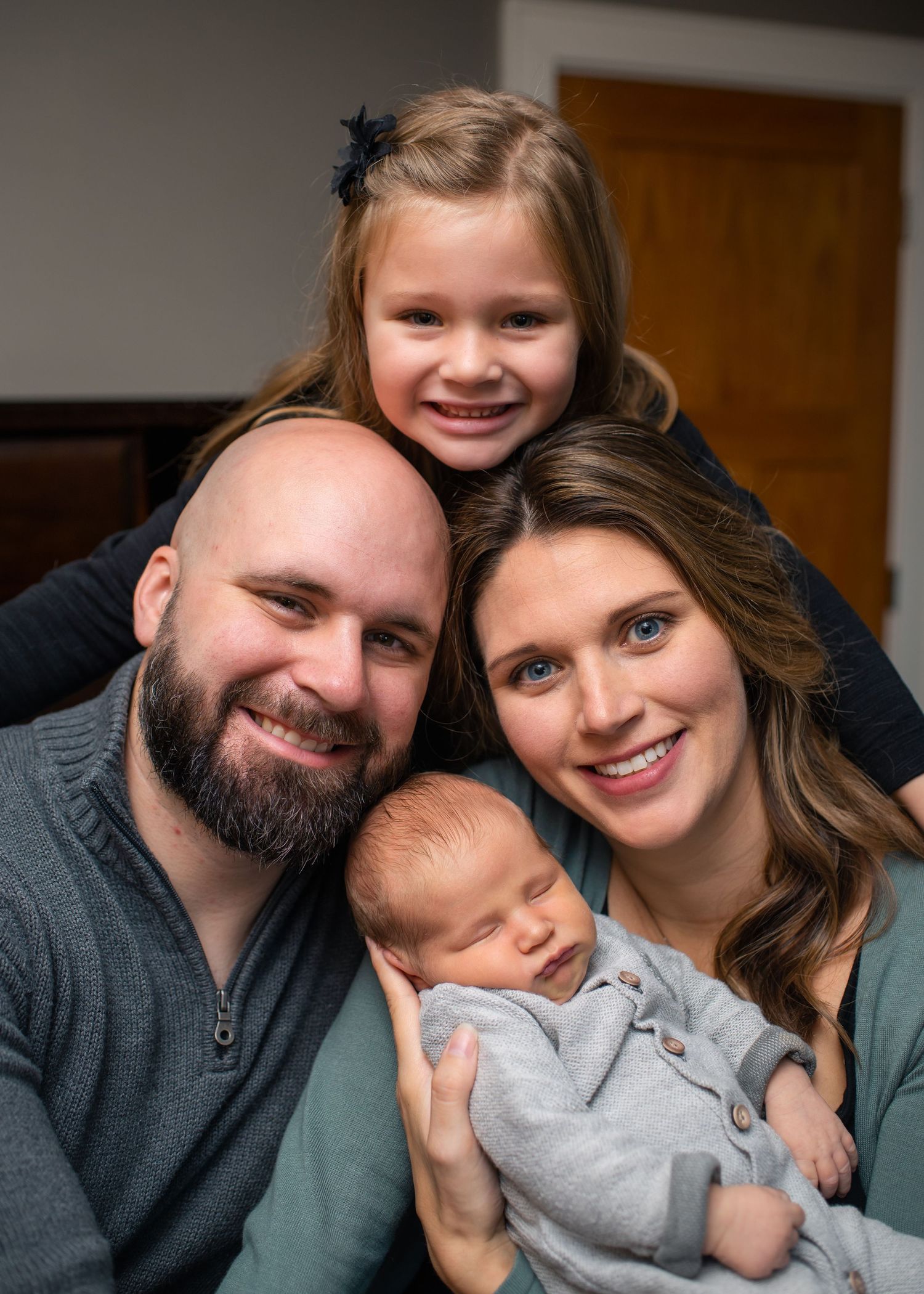 Indoor family portrait with newborn baby showcasing close bonds and warm smiles.