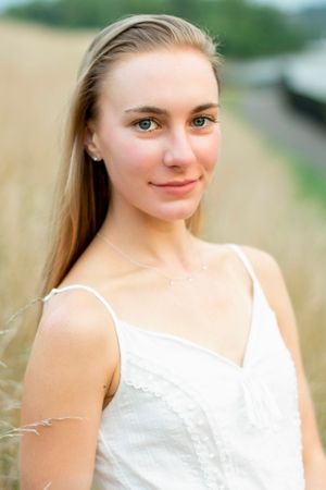Portrait of someone wearing white sundress against natural outdoor background.