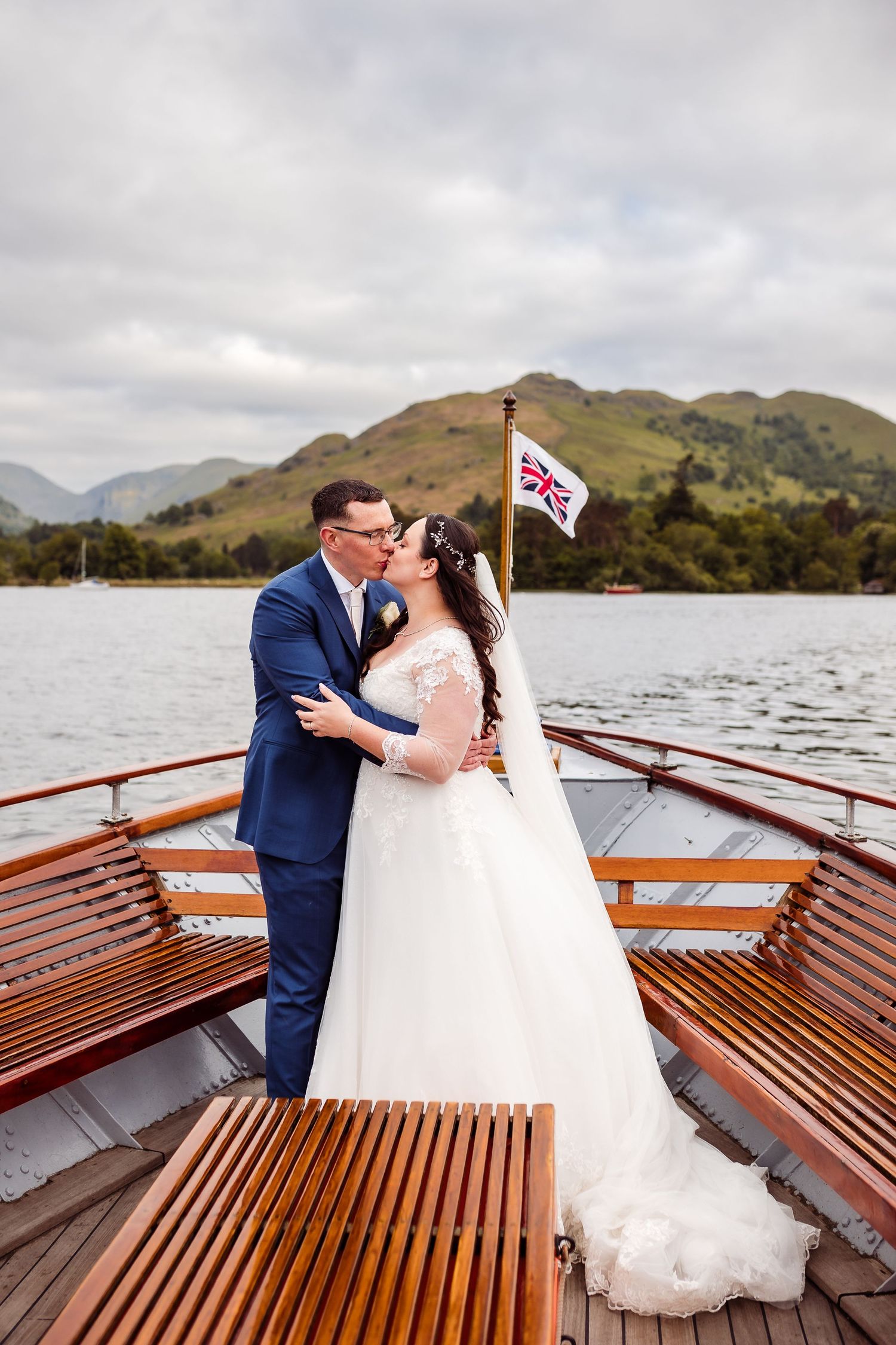 A romantic moment aboard a wooden boat with mountains and lake in the background.