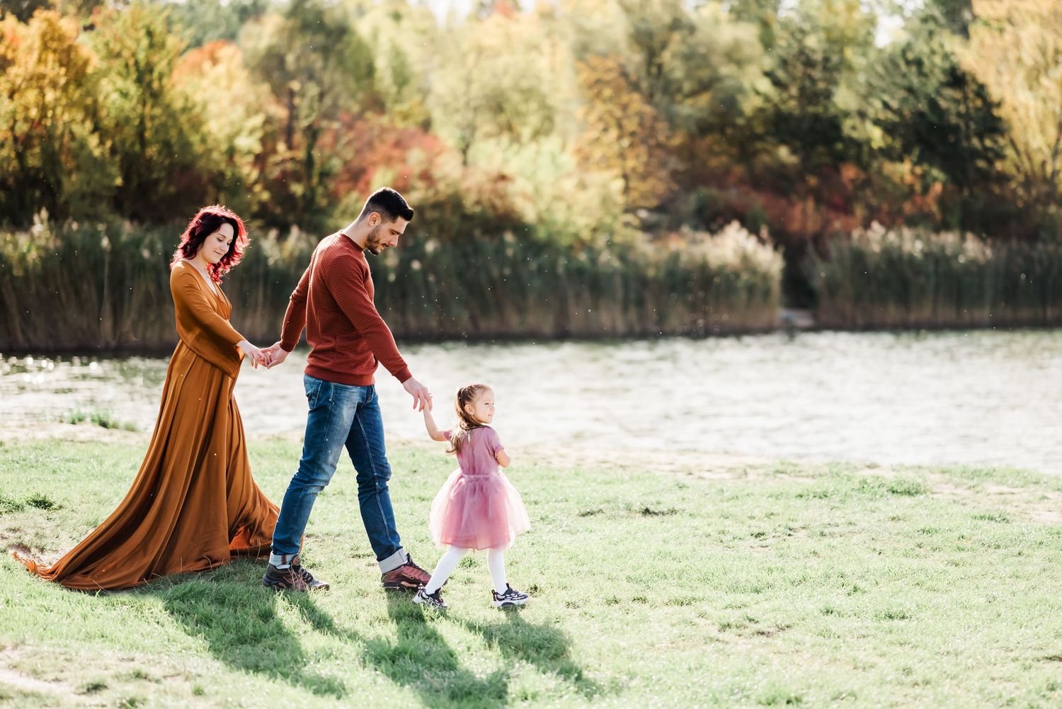 Family of pregnant woman, father and toddler walking in front of a Swiss lake in the canton of vaud