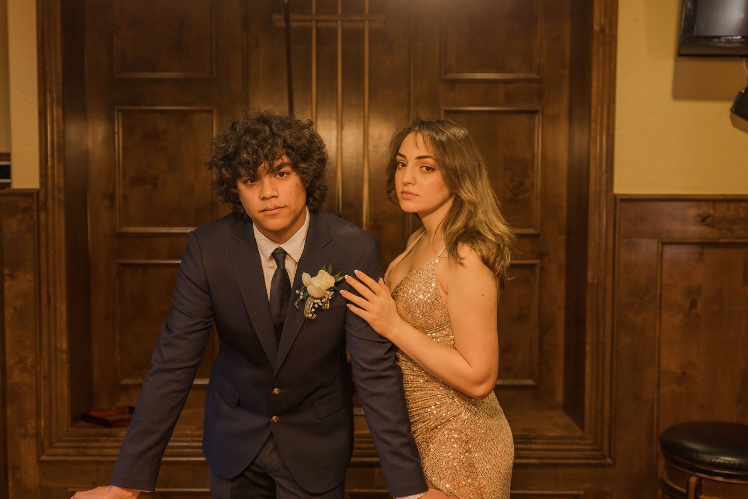 Couple in formal attire posing together in an elegant wood-paneled room.