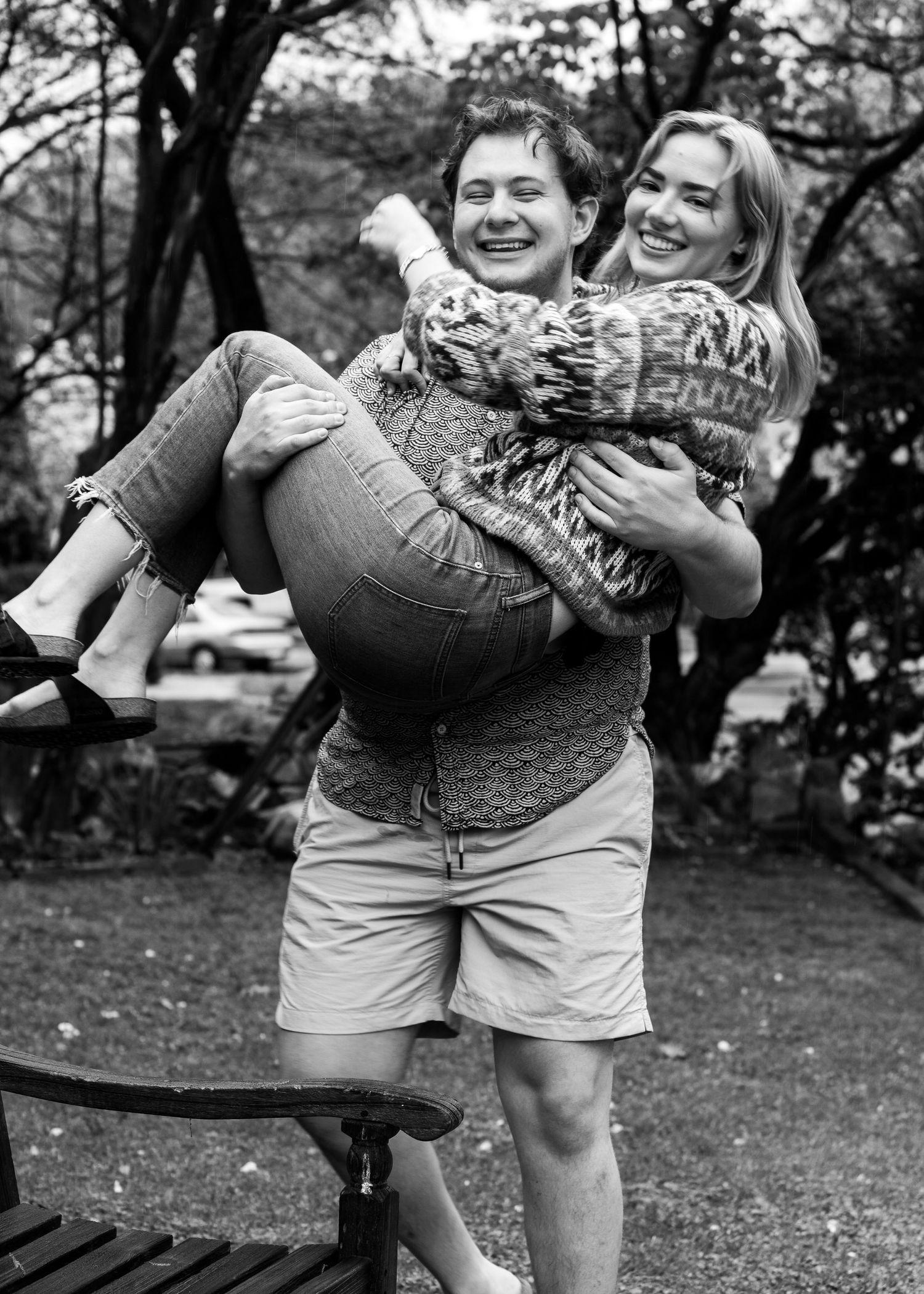 In a soft black and white photo, photographer, Daniel Bowler, holds his partner in his arms and smiles naturally.