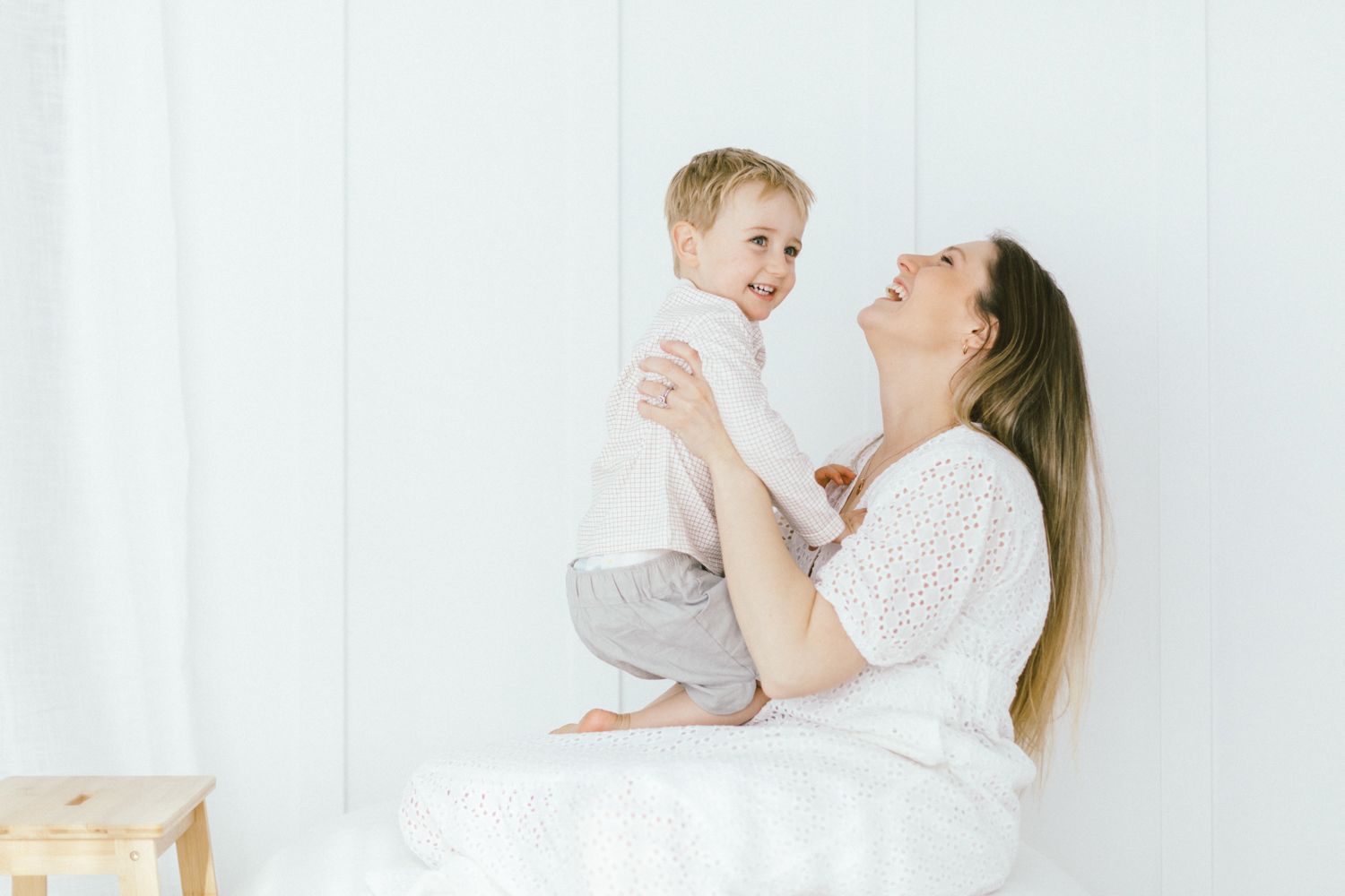 Parent lifts child playfully in the air against white background.