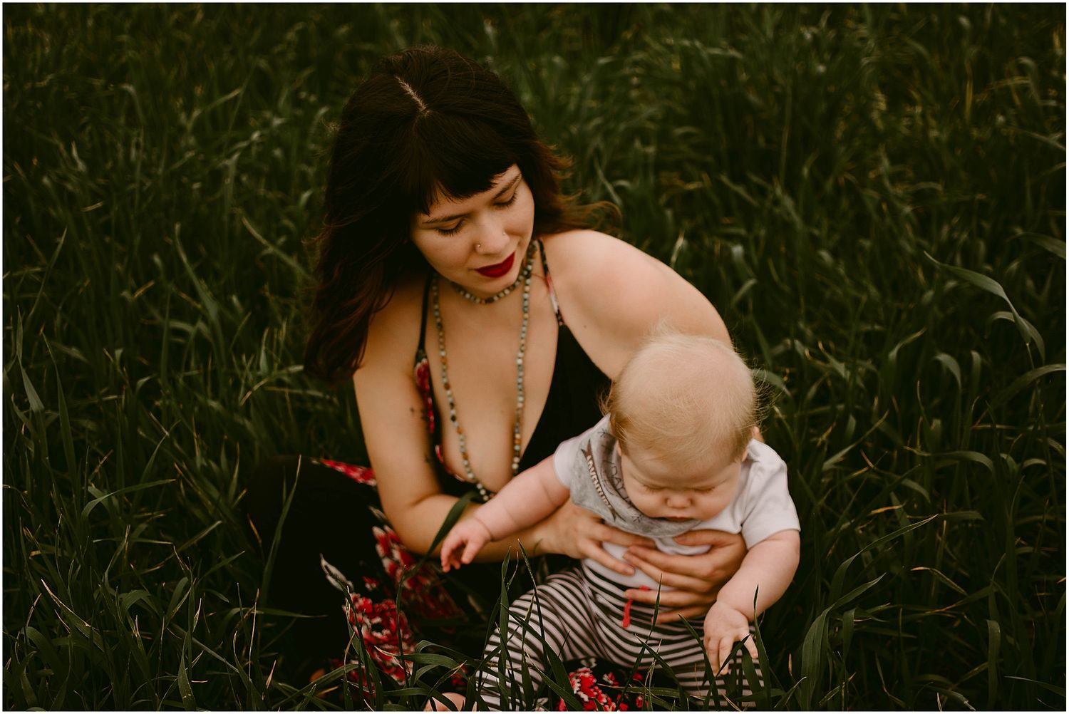 Sweet interaction captured in tall grass wearing summer clothing.