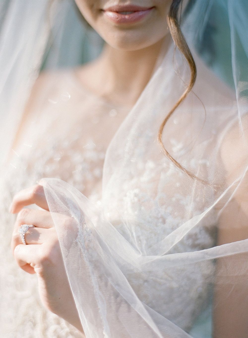 Ethereal close-up of delicate white bridal veil with soft light filtering through.