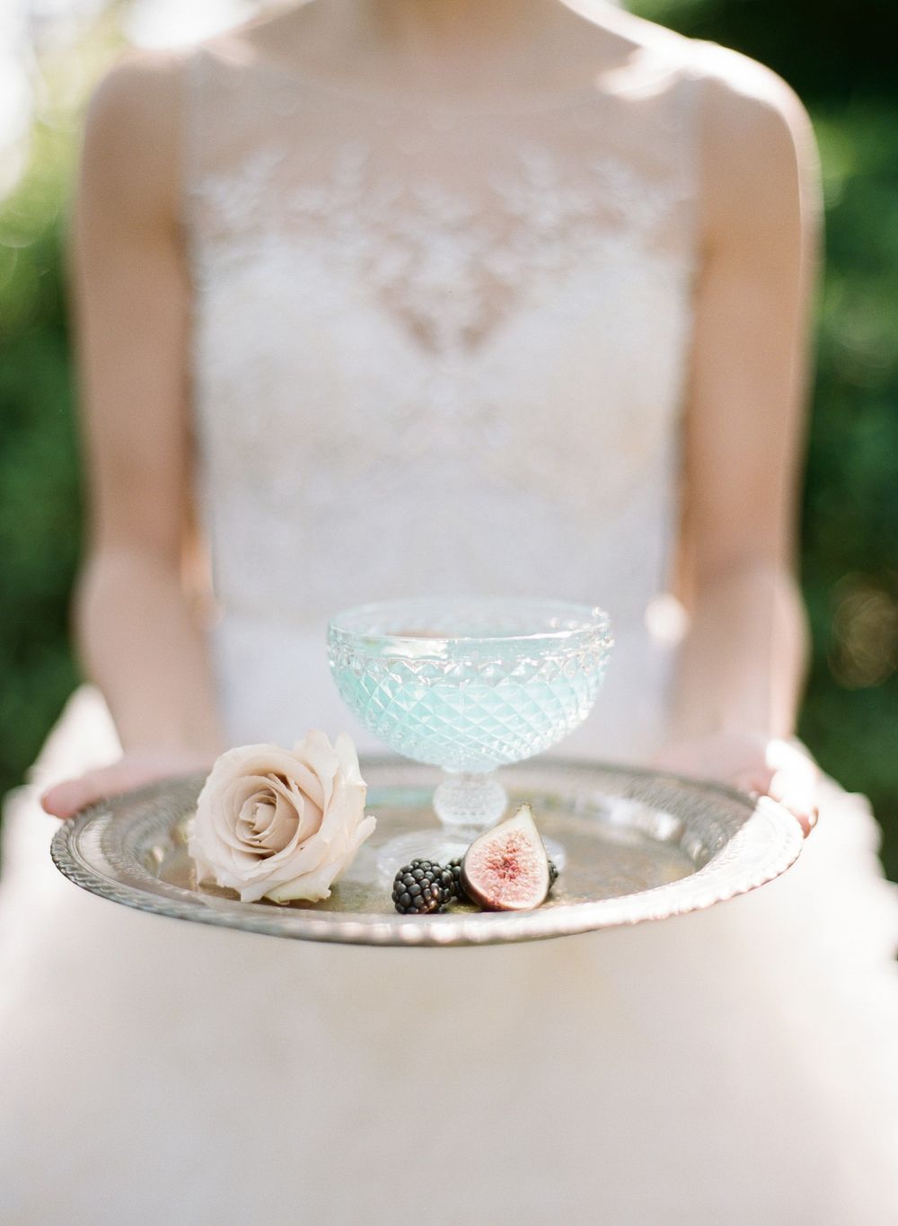 Vintage blue glass bowl and delicate roses displayed on a silver tray with white dress details.