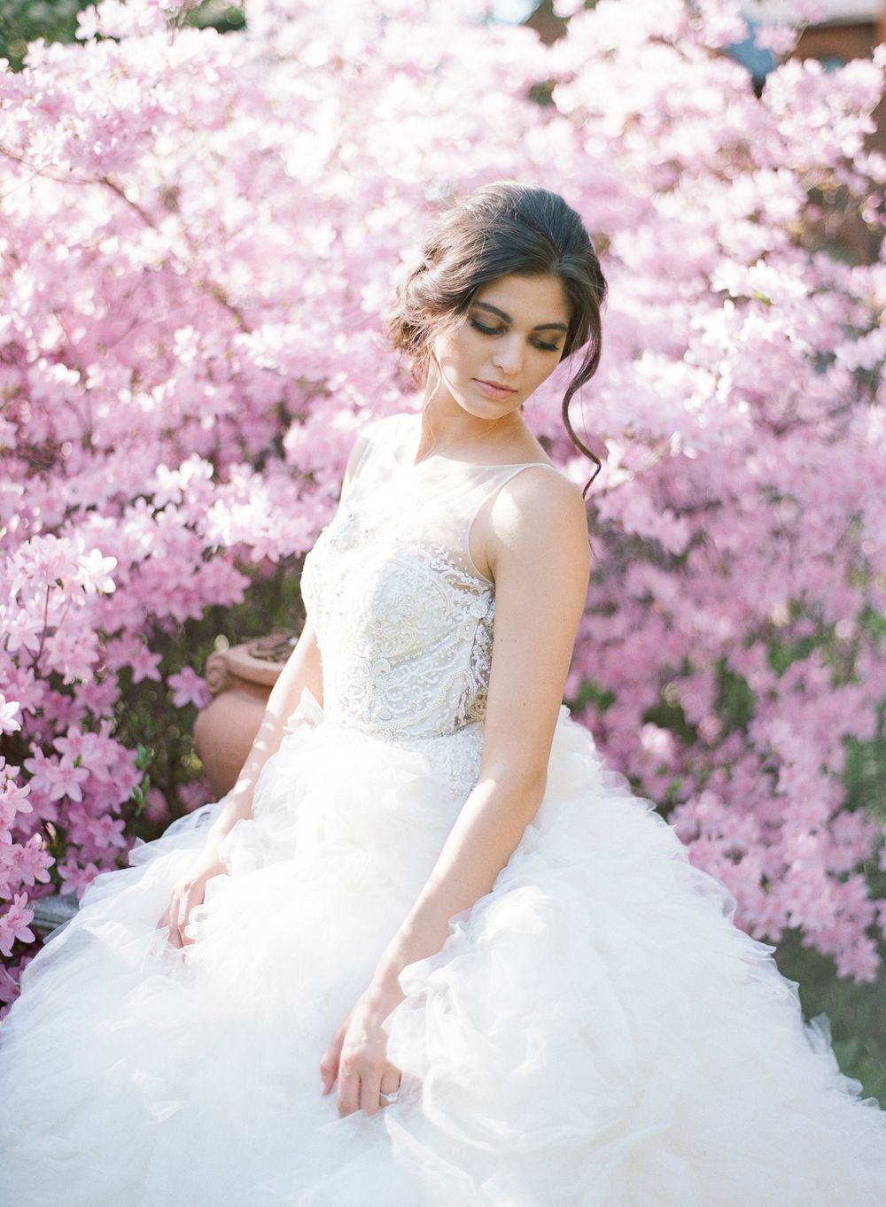 Romantic bridal portrait against blooming pink cherry blossoms in spring.