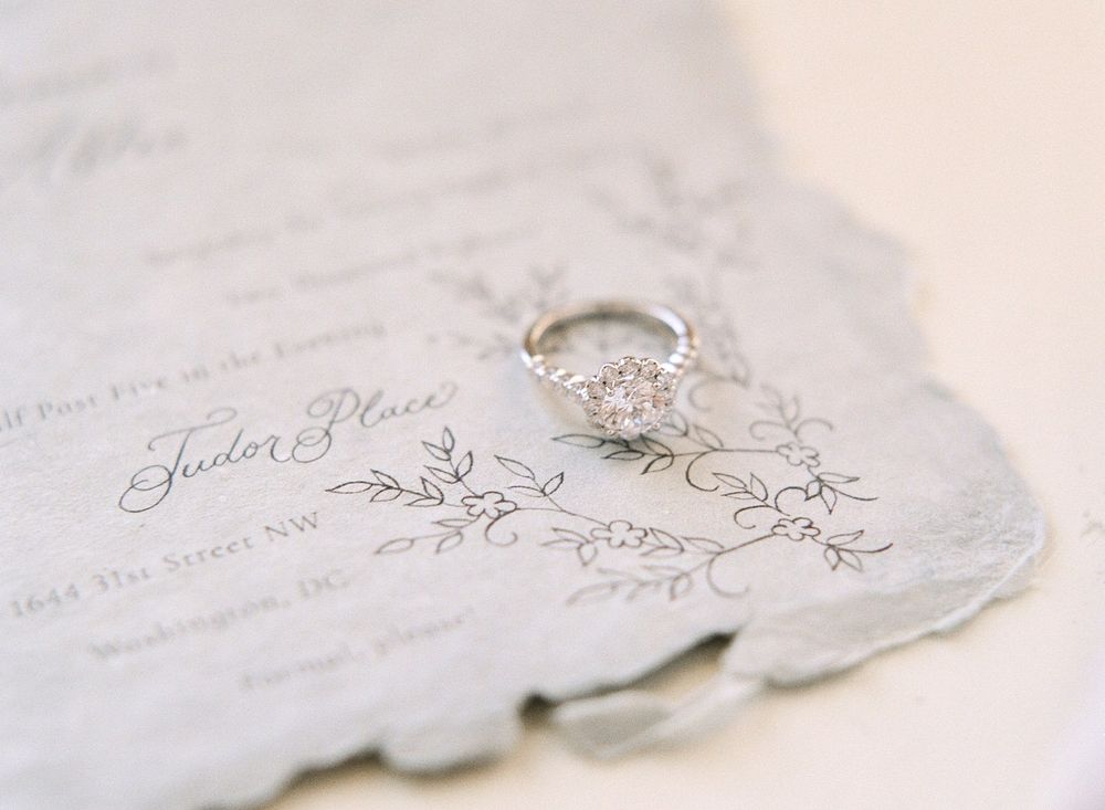 Vintage-style wedding invitation with elegant calligraphy and diamond engagement ring.