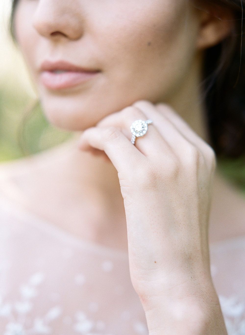 Close-up of a round diamond engagement ring displayed on delicate lace fabric.