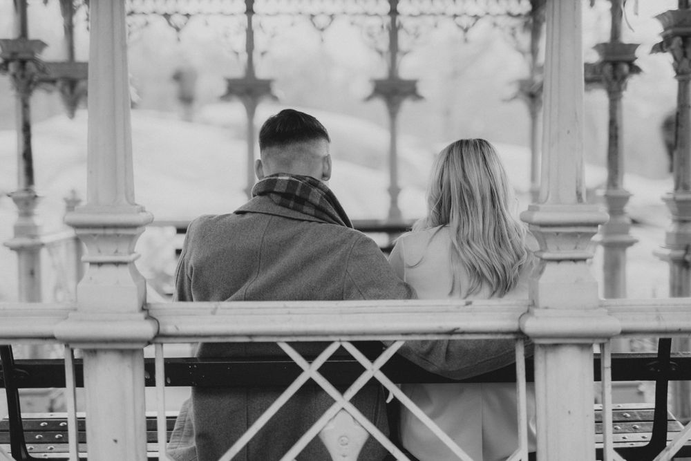 A couple shares joyful moments together by a lake with the city skyline in the background.