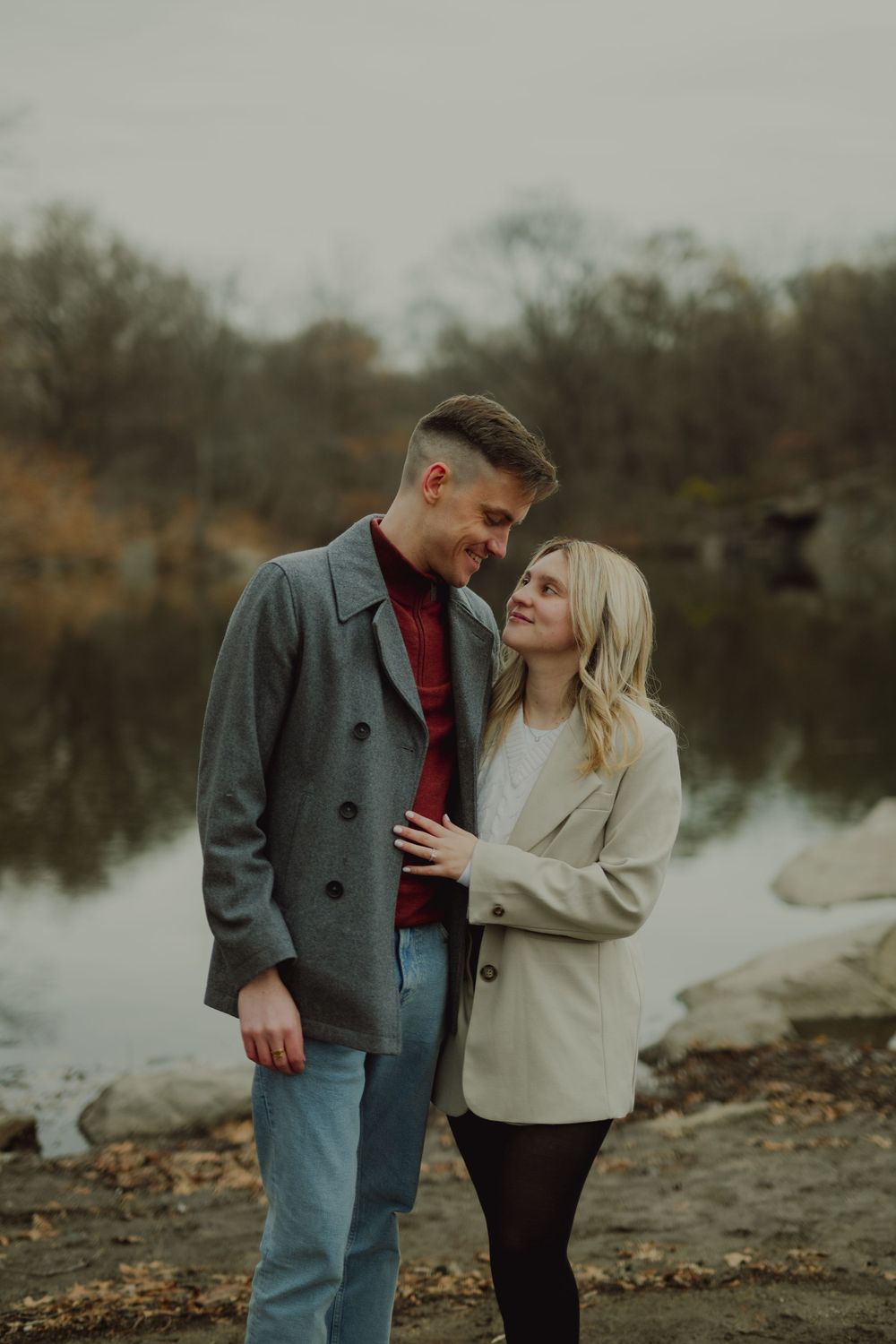 A couple shares romantic moments by a lake during an autumn photoshoot series.