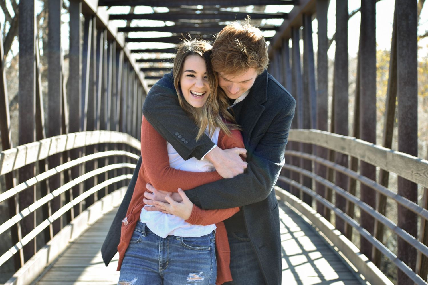 Couple laughing and hugging on a bridge