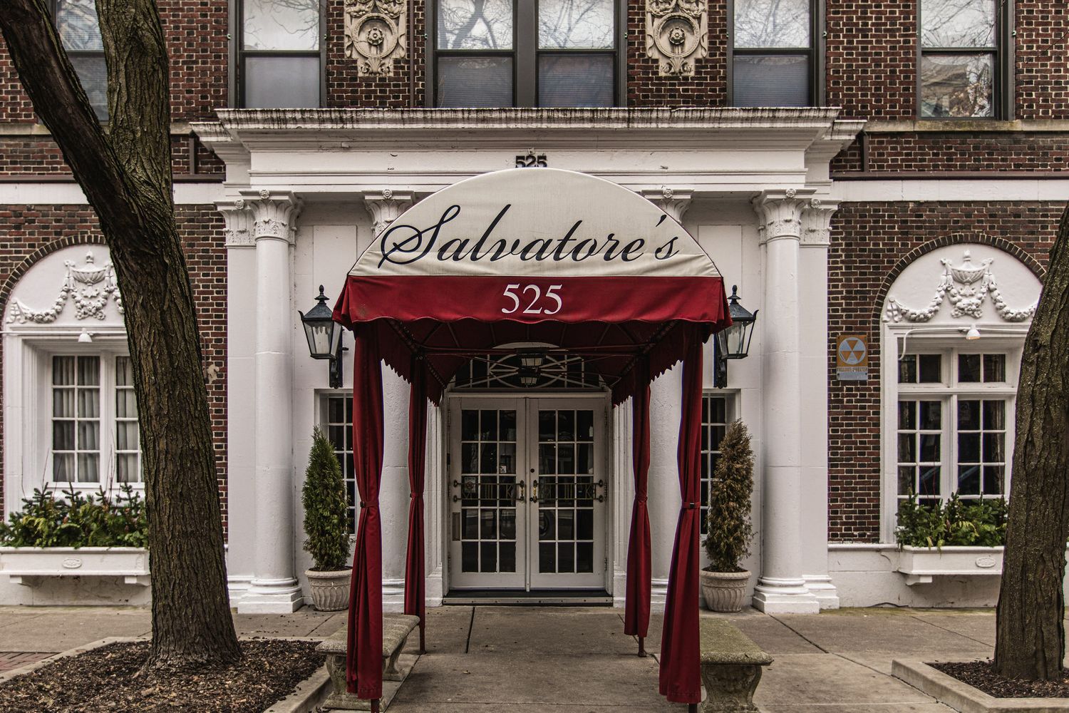 Classic brick building exterior with red and white striped awning at Salvatore's entrance.