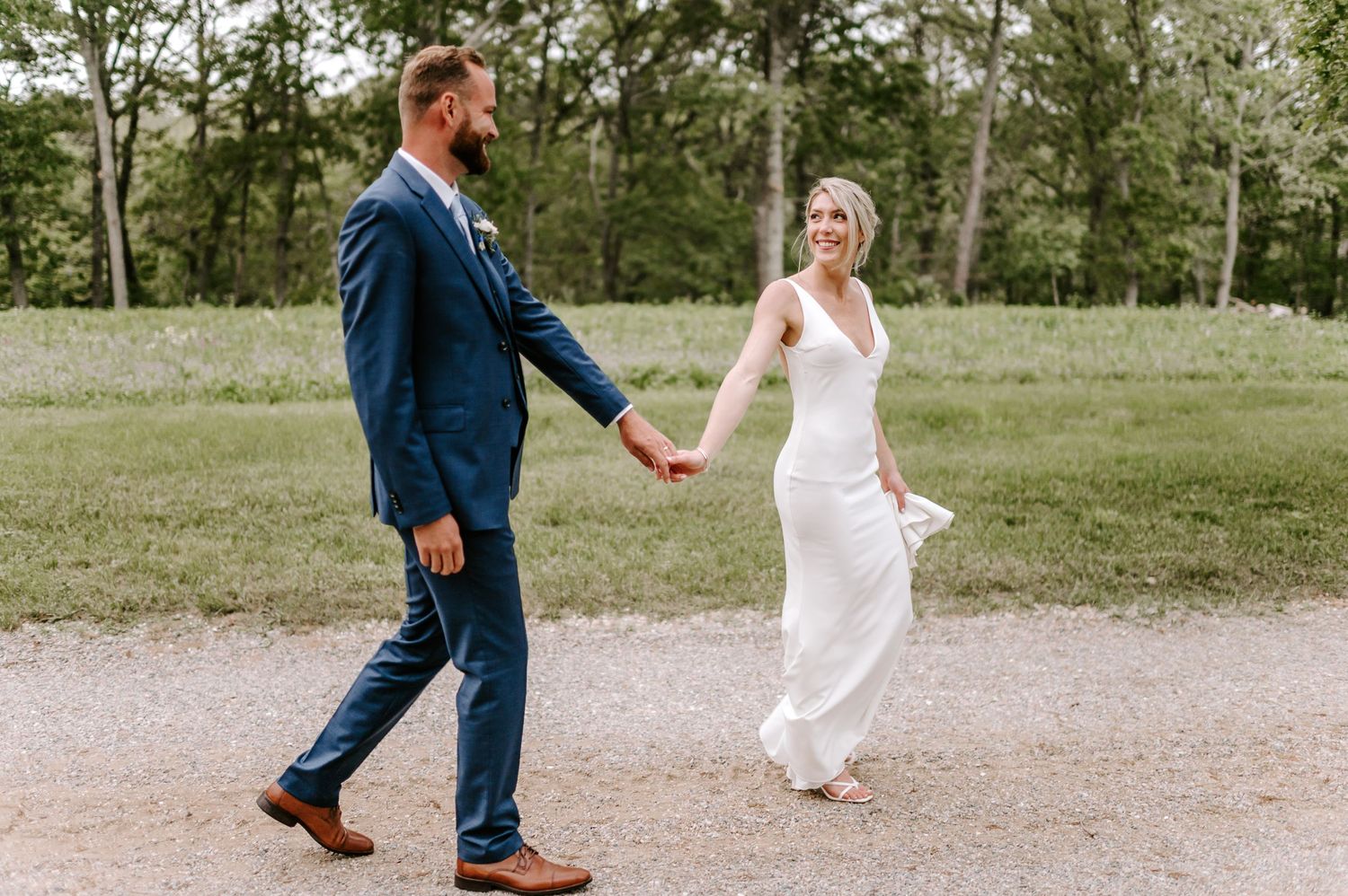 A couple playfully walks and dances together on a winding outdoor path.