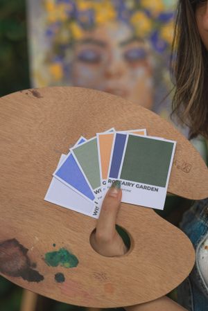 Wood painting palette with color swatches displayed against blurred floral artwork background.