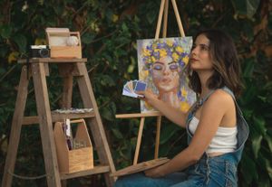 Artist working on a colorful portrait painting outdoors with art supplies on a wooden ladder.