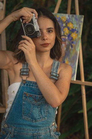 Creative outdoor photography session featuring an artist with vintage camera and floral painting.