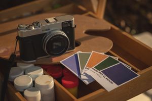 Vintage camera and art supplies arranged in a wooden box.