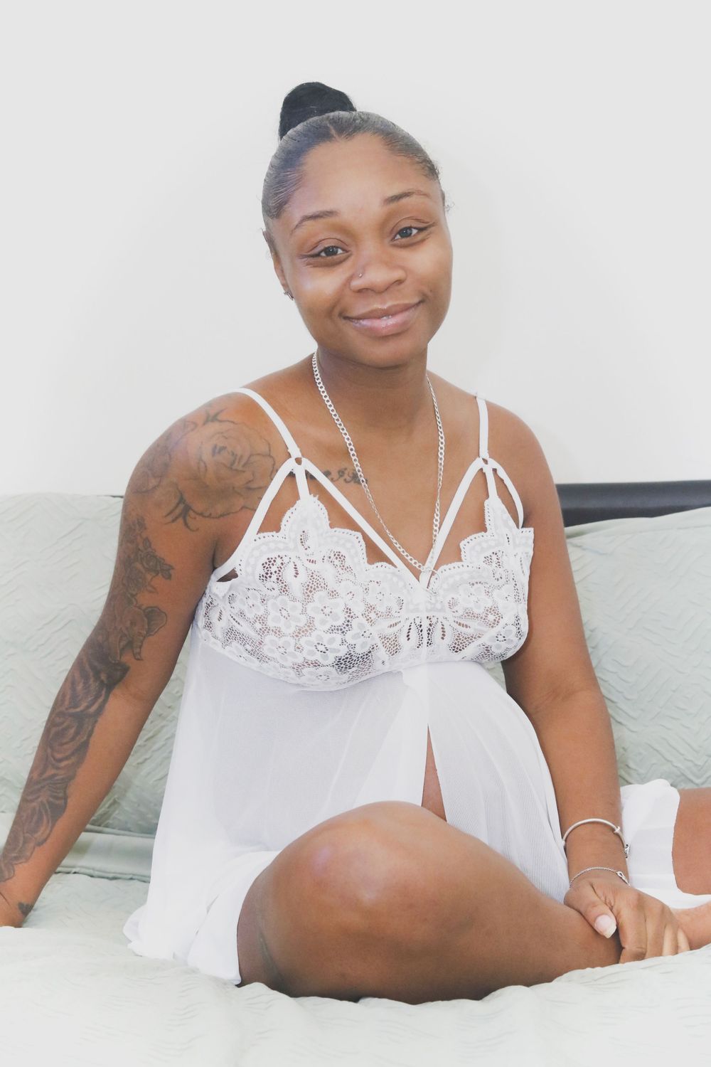 Intimate boudoir photo session featuring white lace lingerie on a light colored bed.
