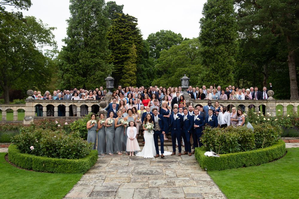 Wedding party gathered on stone steps in lush garden setting during outdoor celebration.
