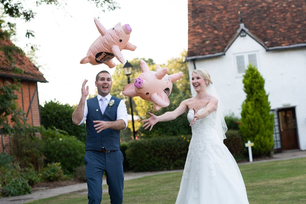 Wedding couple shares candid moments outside brick building with white trim.