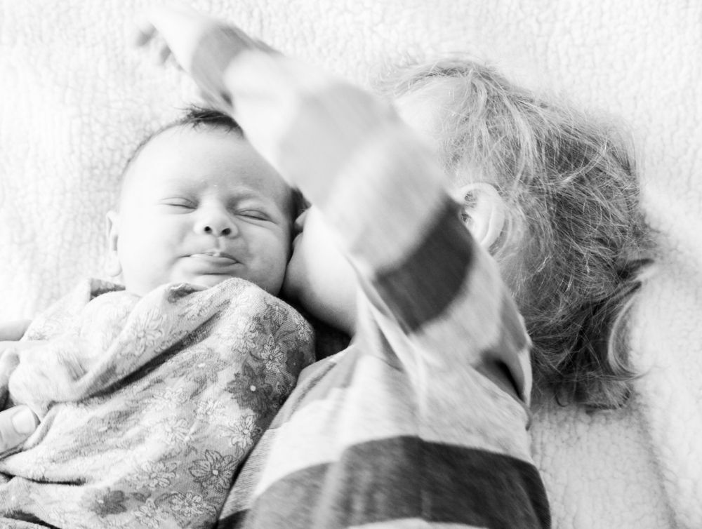 Series of black and white photographs capturing intimate resting moments on white fabric.