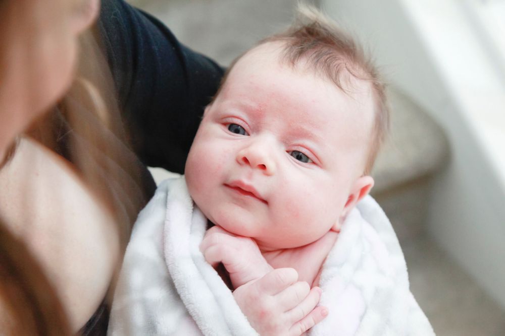Sweet portraits of an infant with bright eyes and rosy cheeks against white background.