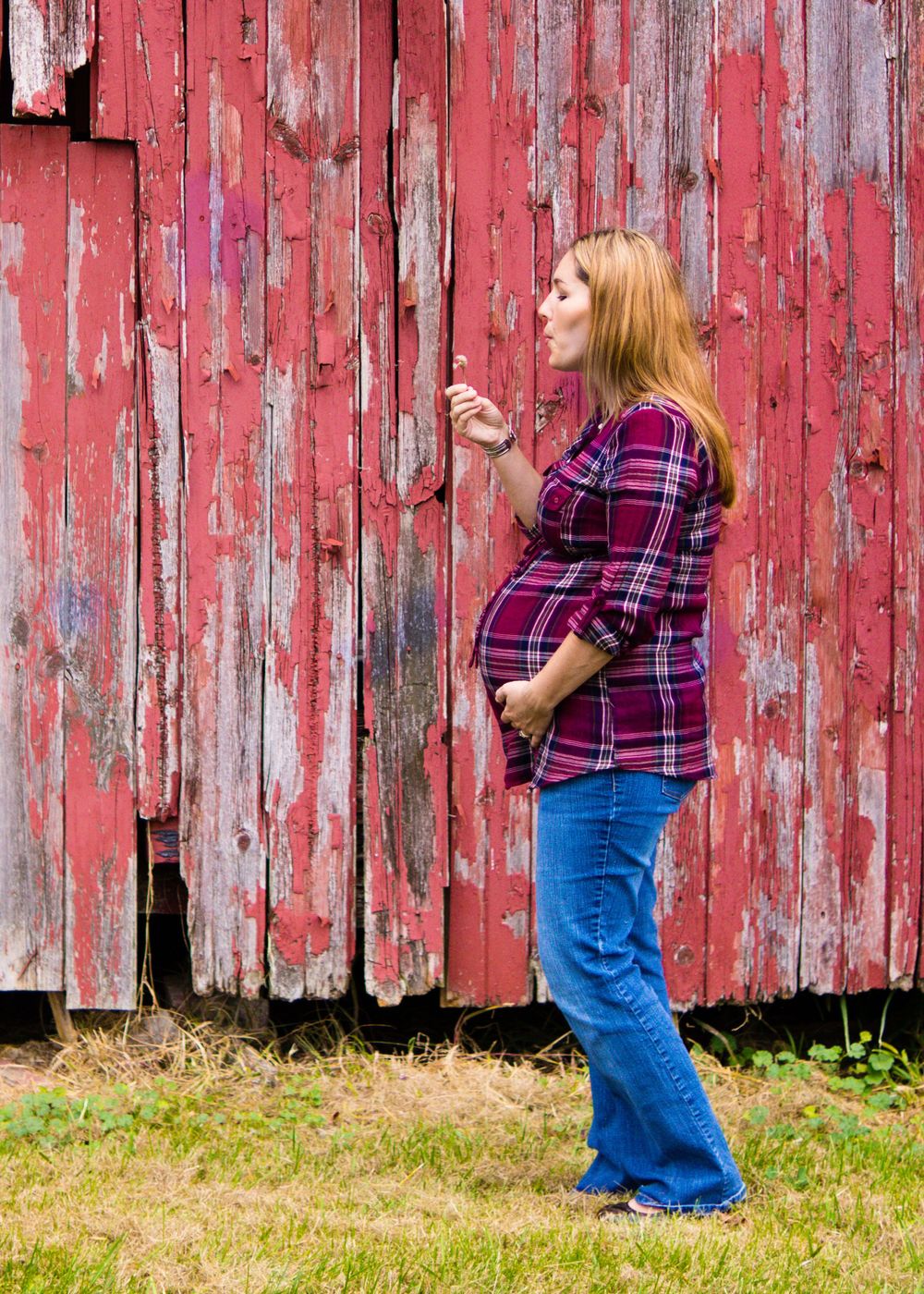 Outdoor photo of pregnant woman blowing bubbles by a barn during a maternity session by professional maternity photographer in Dandridge
