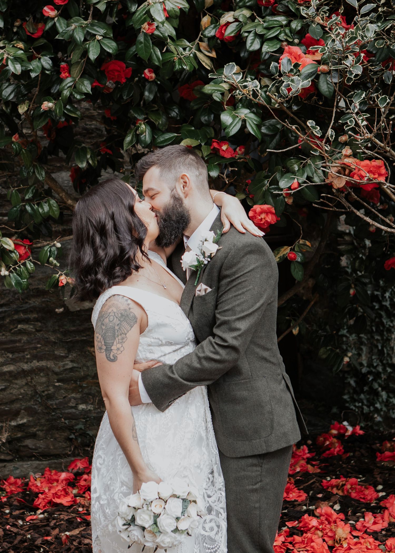 Bride and Groom kiss at Devon wedding flowers in background