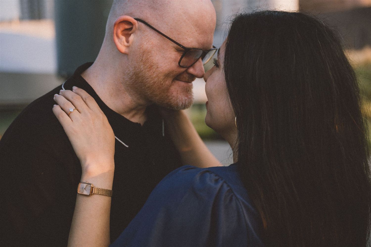 A close-up romantic moment between a couple against an urban backdrop.