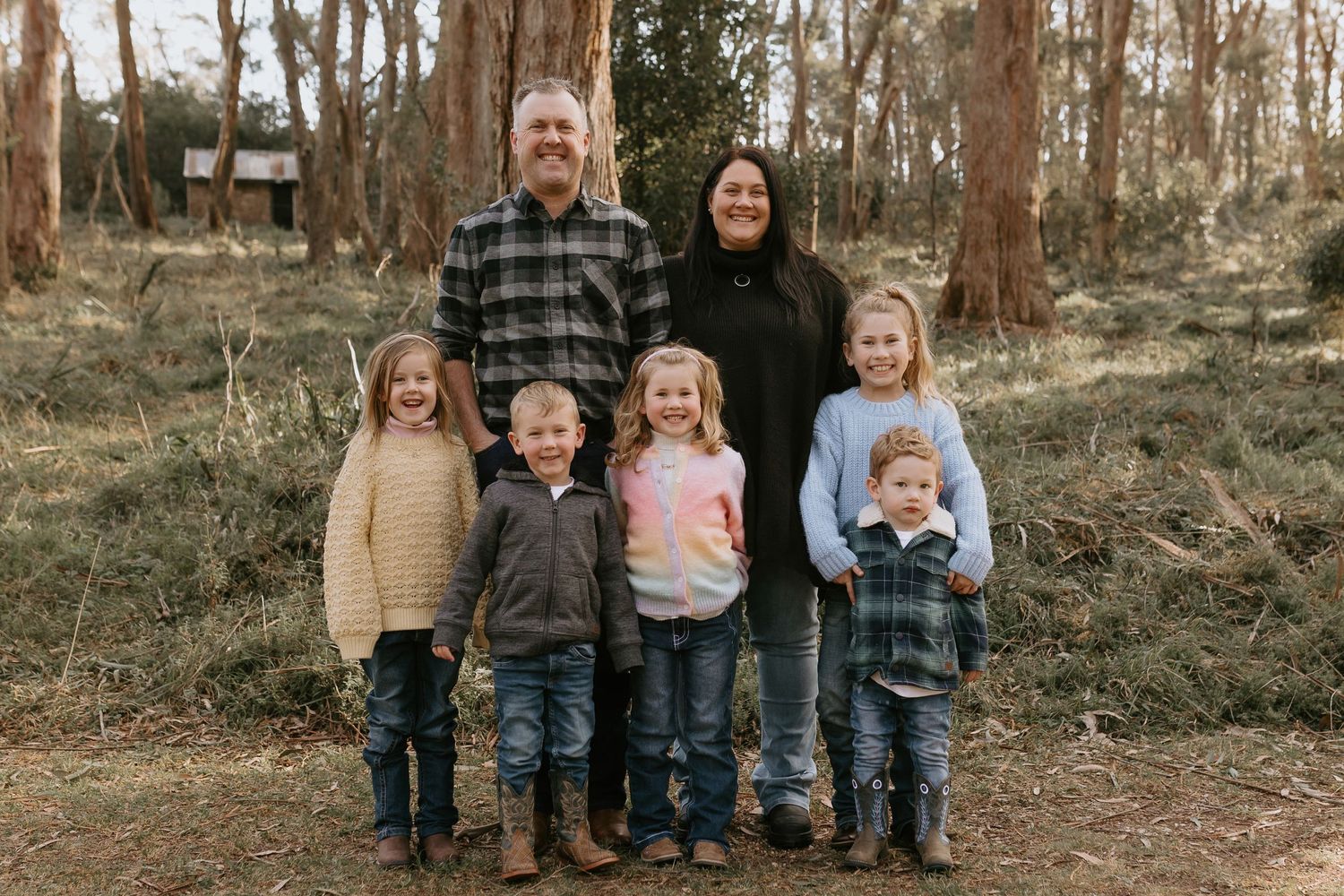 Group photo of children lined up outdoors in wooded setting wearing casual clothes.