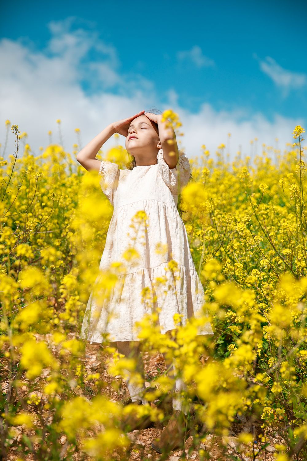 A girl in a field of yellow flowers enjoys the rays of the sun