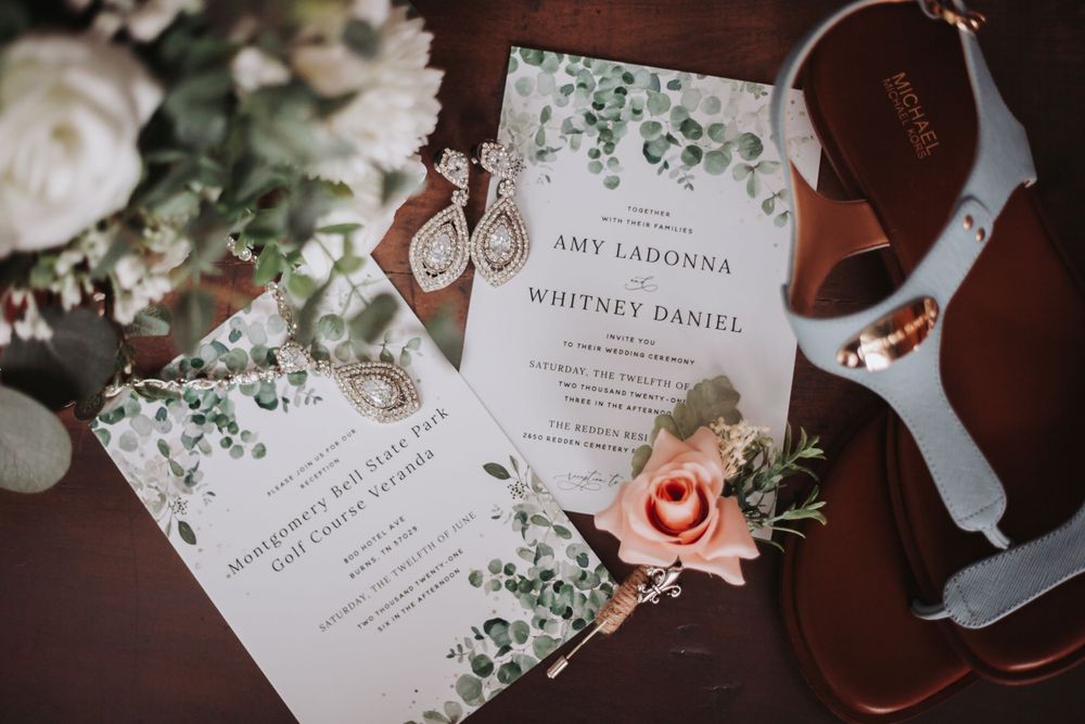 Elegant wedding invitation with floral details and eucalyptus design alongside bridal shoes.