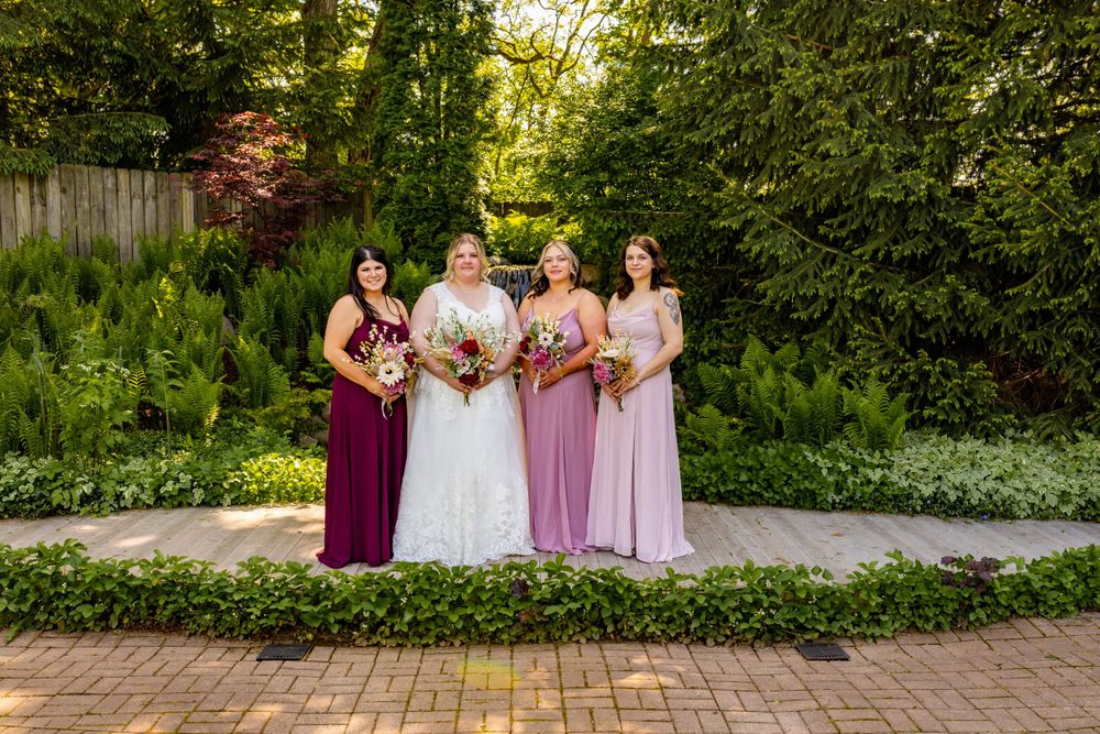 A wedding party poses in a lush garden setting with coordinated pink and purple dresses.
Janesville, WI
Brodhead, WI