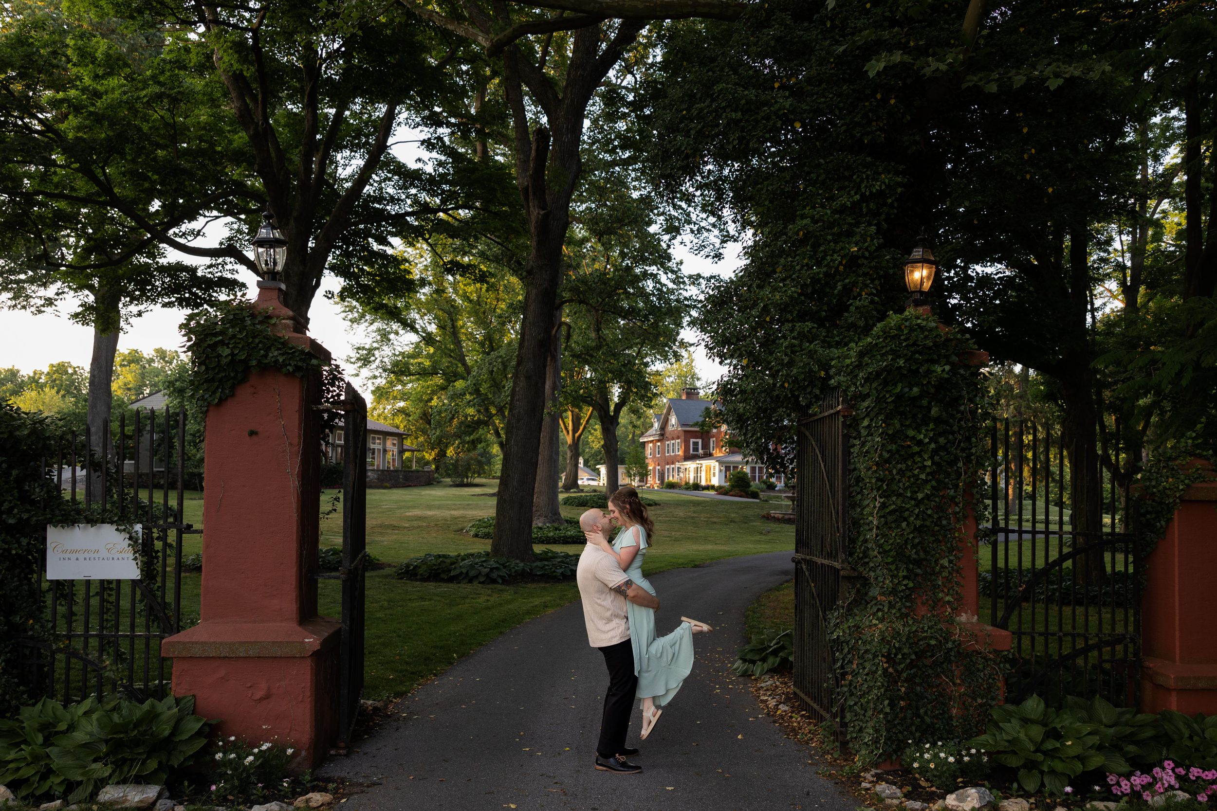 A romantic evening portrait by historic iron gates with glowing lanterns overhead.