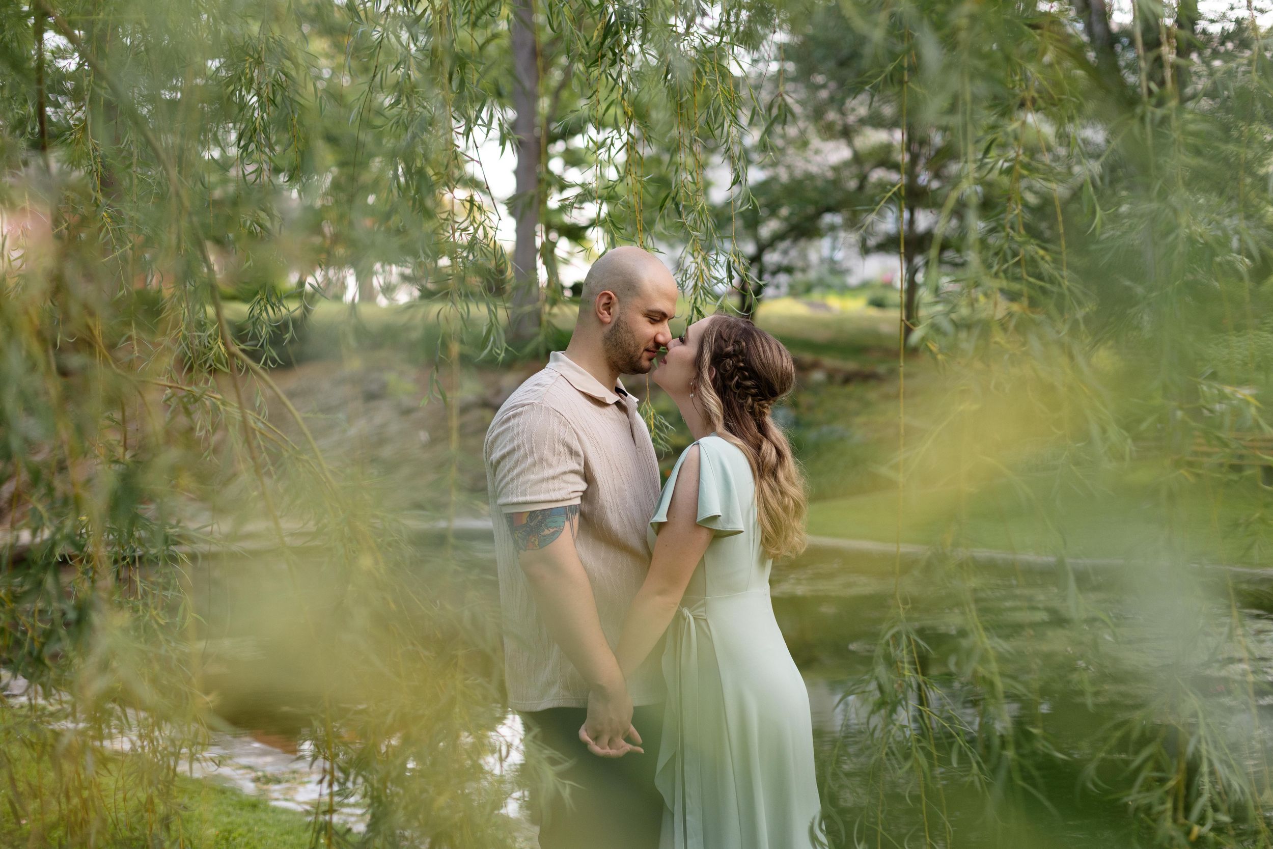 Intimate moment captured through leaves at a garden photoshoot.
