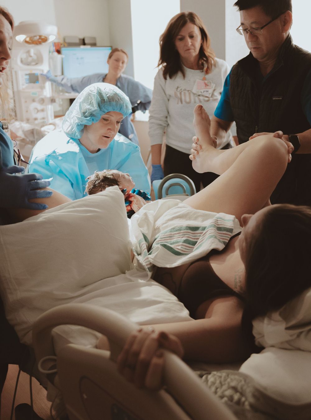 Medical team gathered around patient during delivery in hospital setting.