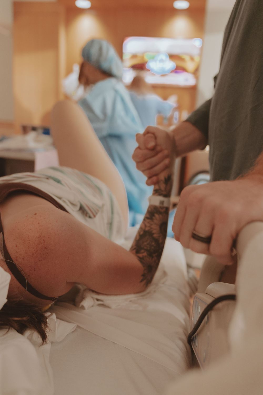 Medical staff attending to patient in delivery room while holding hands for support.