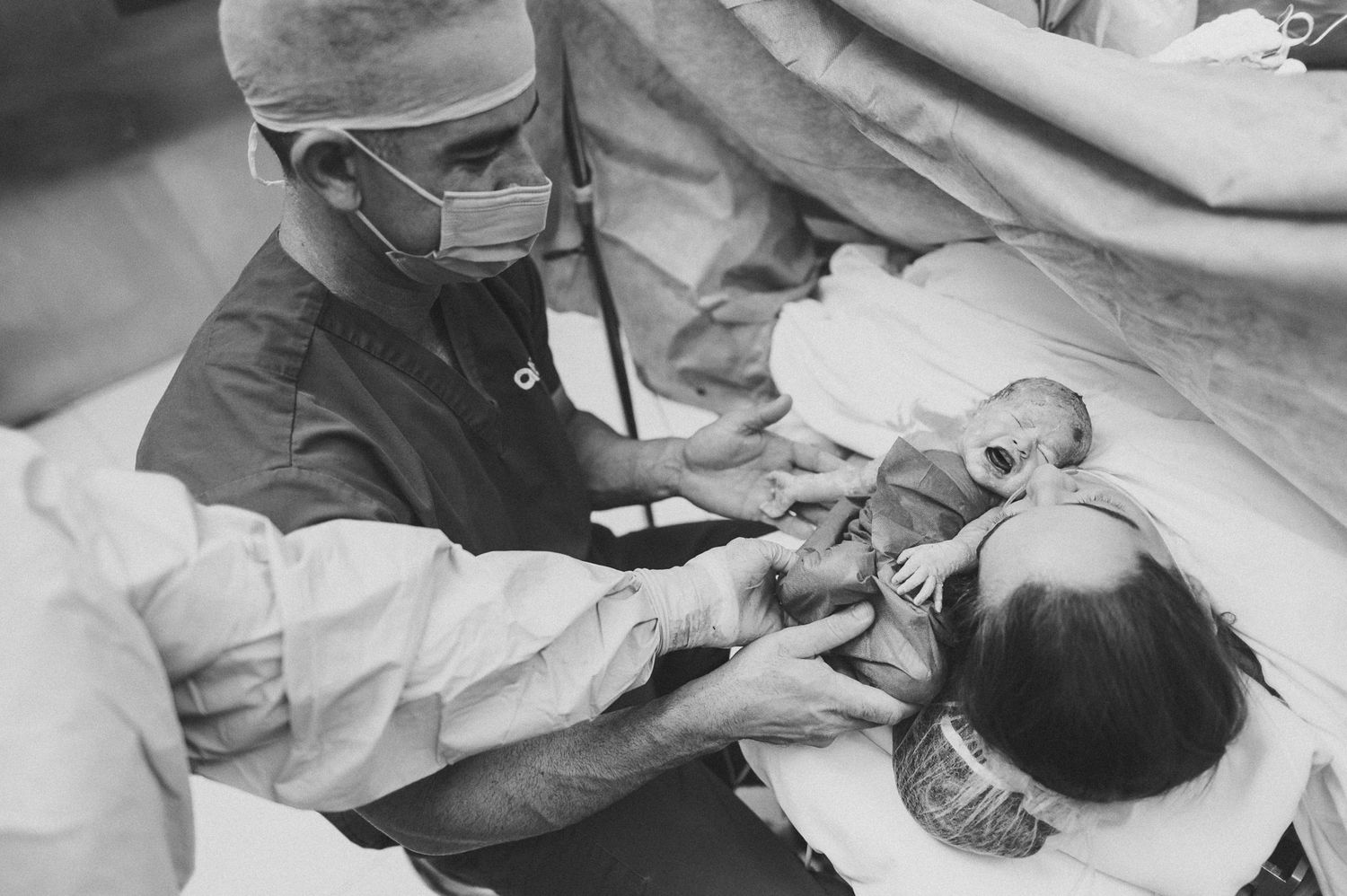 Healthcare provider in surgical mask and cap performing medical procedure.