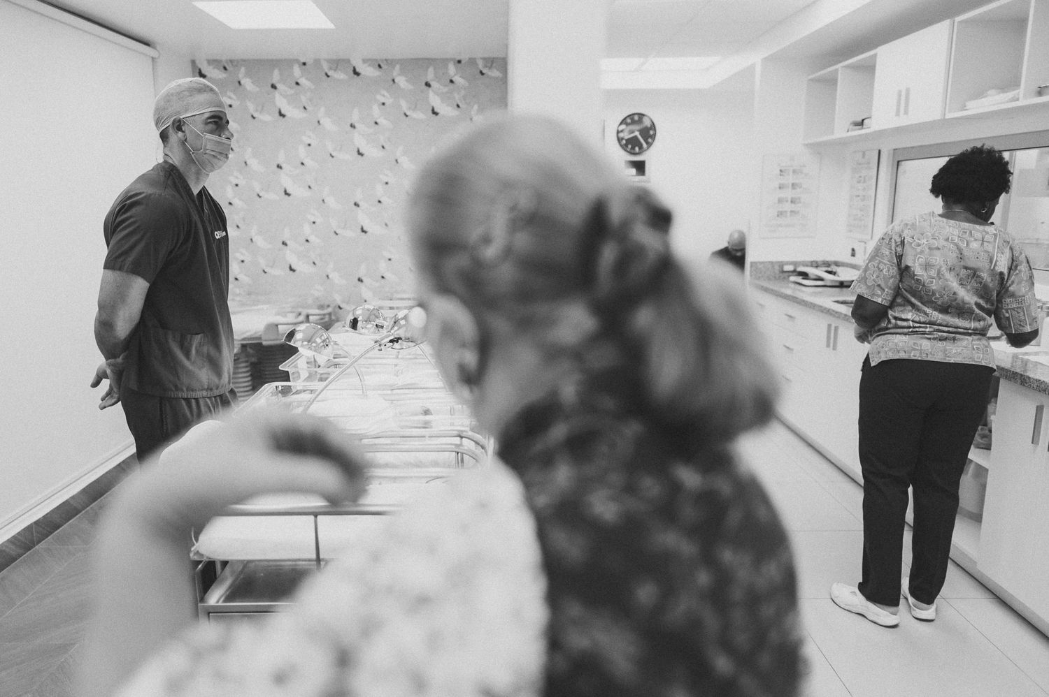 Hospital staff attending to newborns in modern nursery setting with medical equipment.
