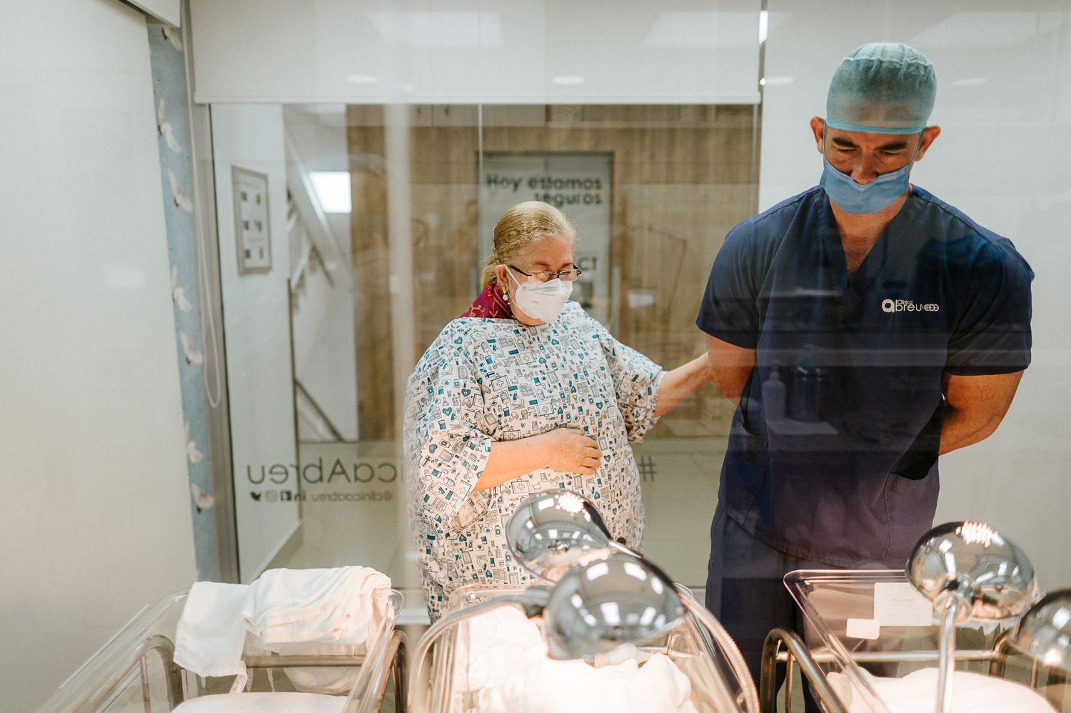 Medical professional in scrubs assists patient in hospital delivery room setting.