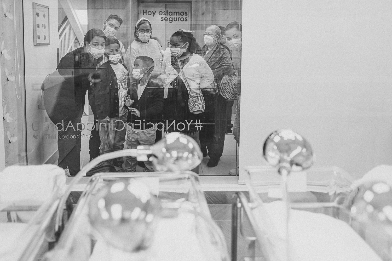 Group of people gathered at a hospital nursery window viewing newborns.