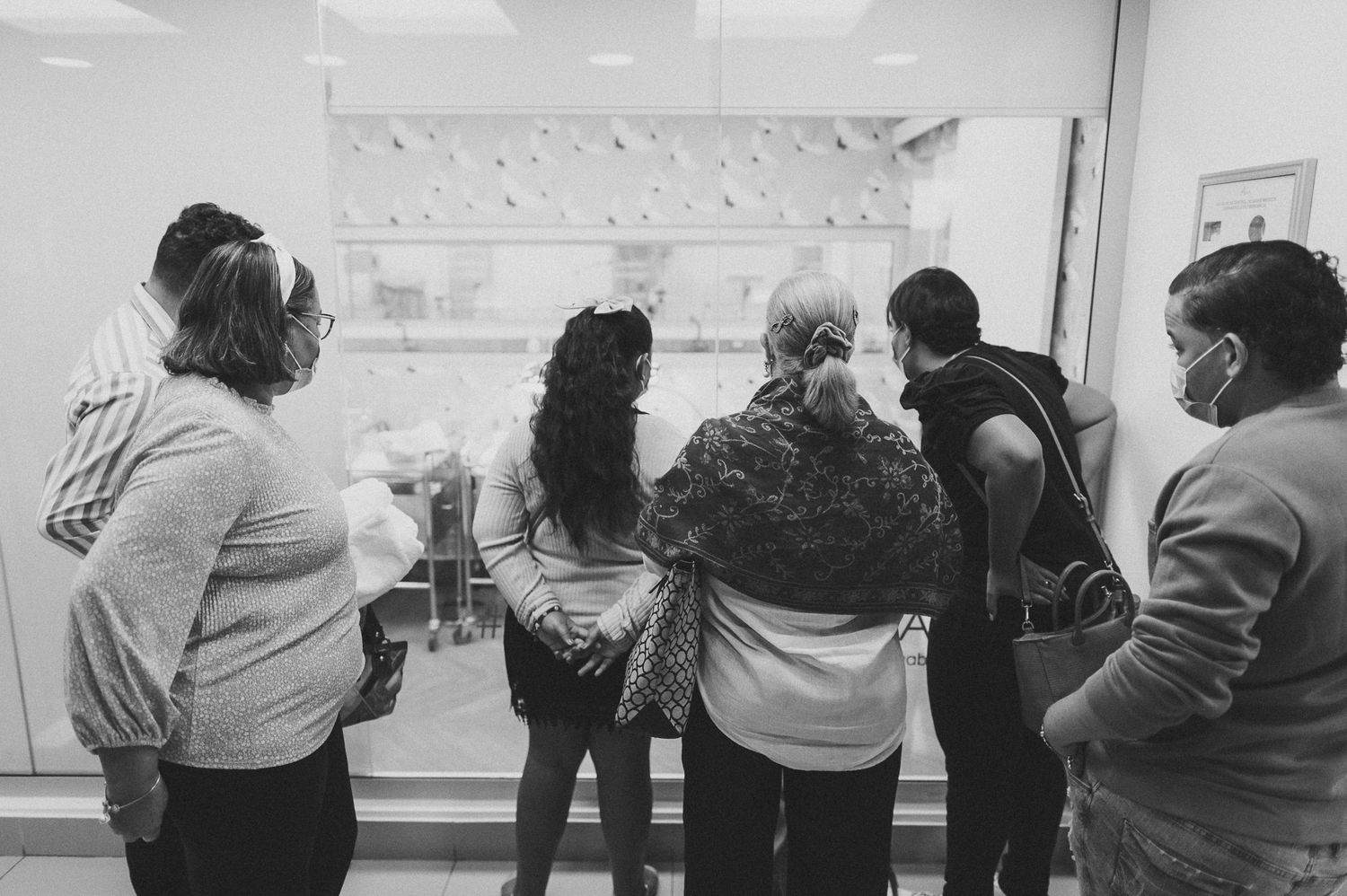 People standing in a hospital hallway looking at something off-camera.