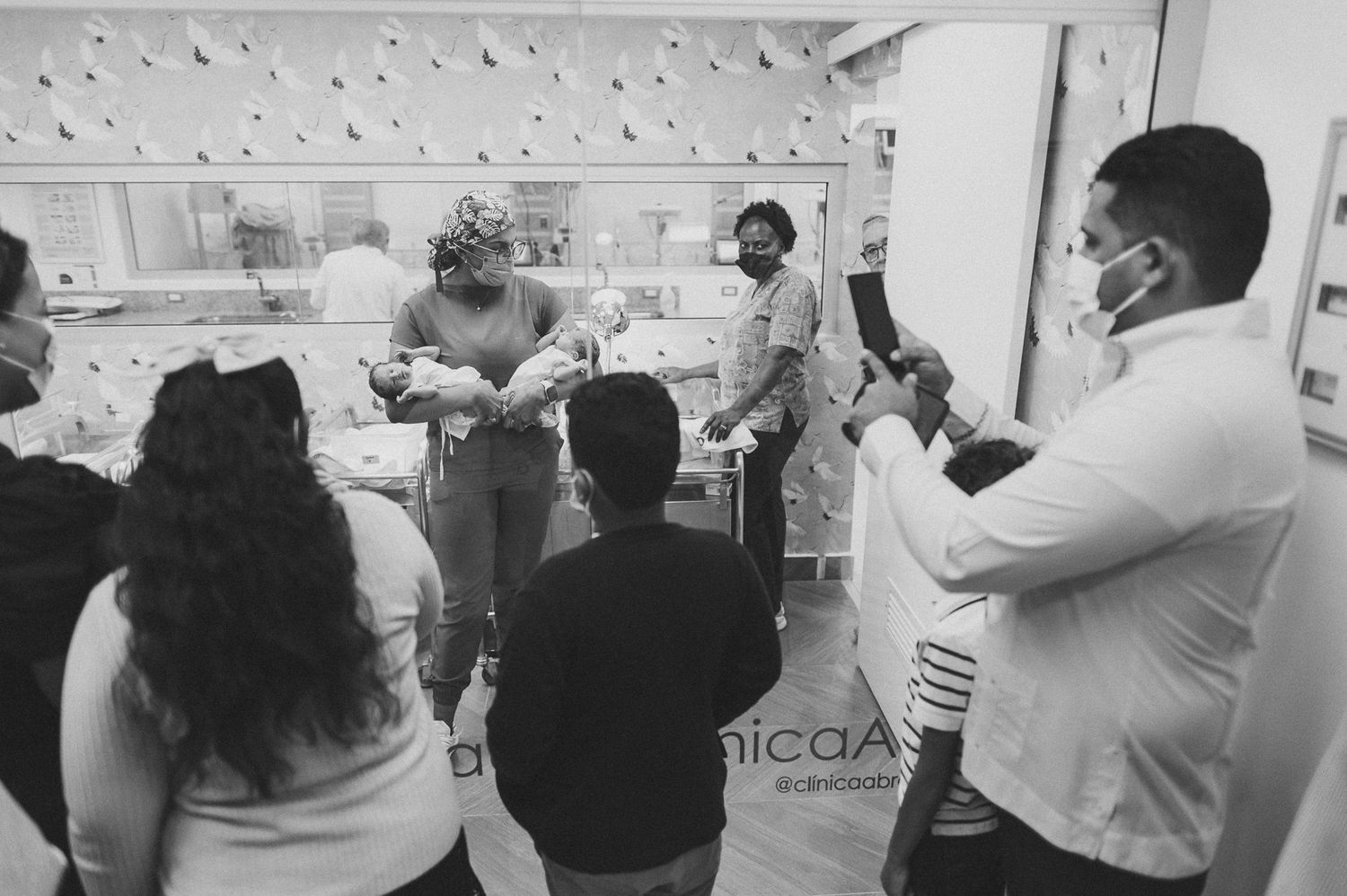 Group gathered in a hospital room with medical equipment visible.
