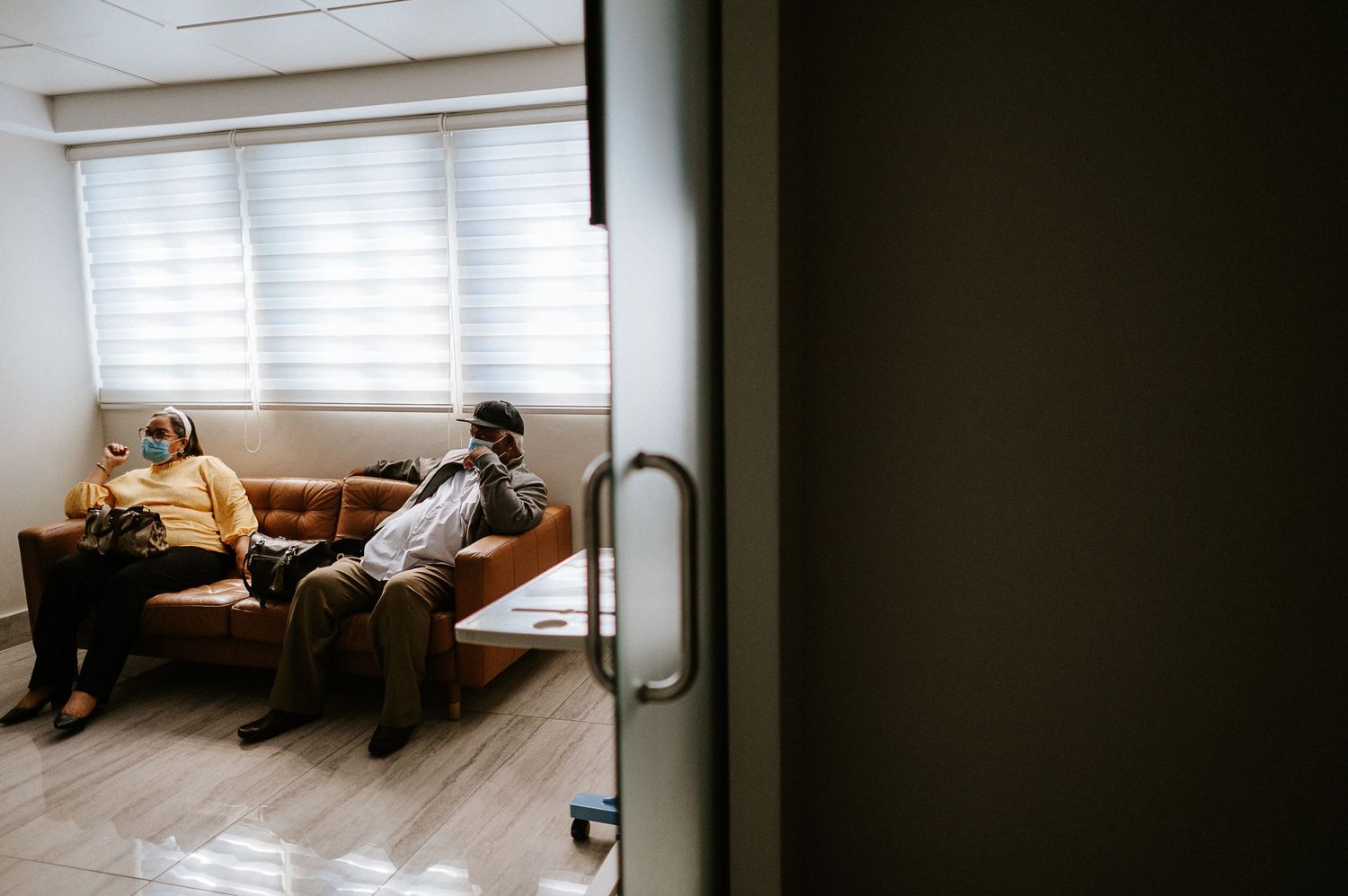 People sitting on a couch in a bright hospital waiting room.