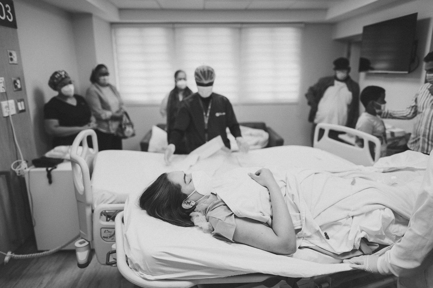 Healthcare workers attend to patient in hospital room during medical procedure.