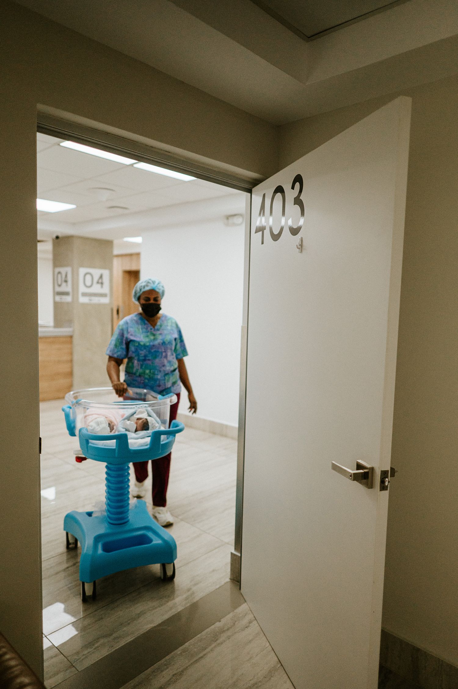 Healthcare worker pushing medical cart through hospital hallway past room 403.
